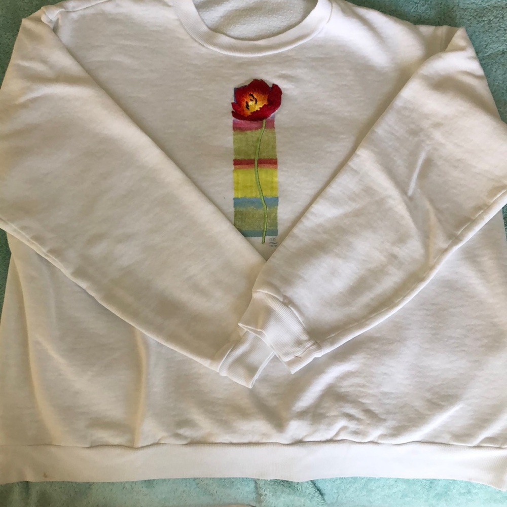 Beautiful embroidered poppy flower with pattern behind on lady’s sweatshirt